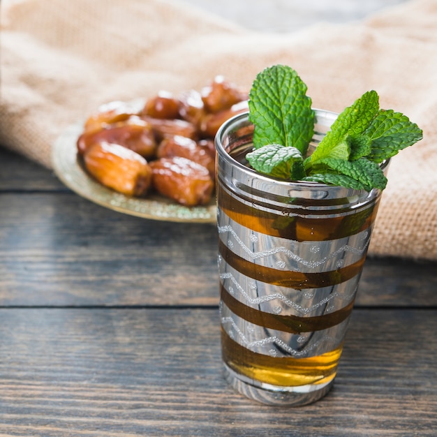 Mug of drink near dried fruits on saucer and burlap