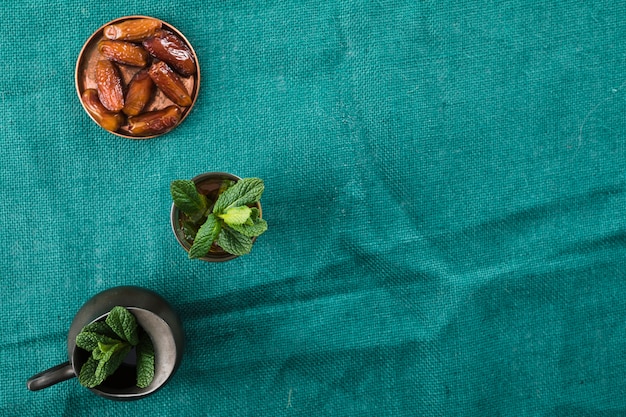 Free photo mug of drink near pitcher with plant and dried fruits