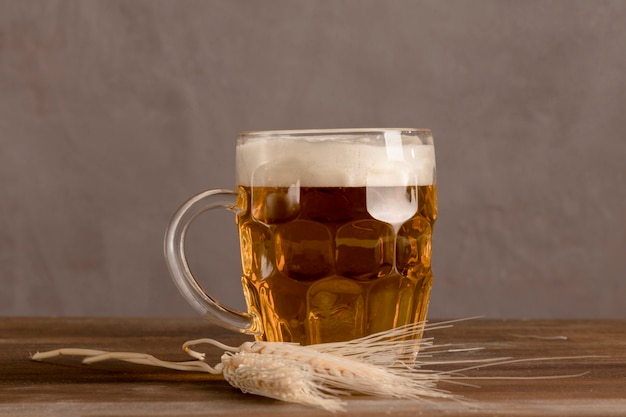 Mug of light beer with wheat on wooden table 