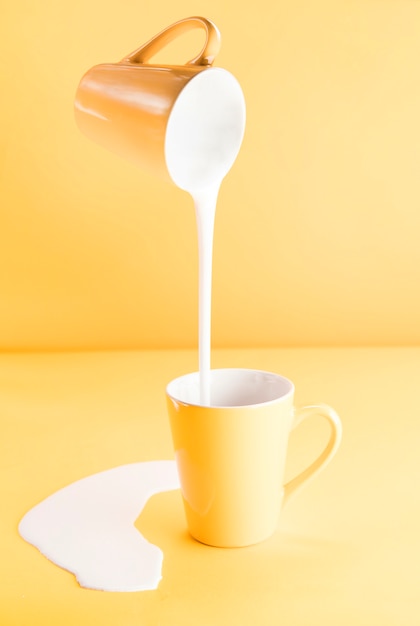 Free photo mug pouring milk into another mug