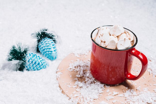 クリスマスおもちゃの近くの雪の間のスタンドにマシュマロとマグカップ