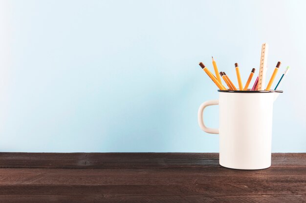 Mug with pencils and ruler on table