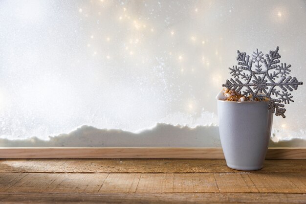 雪と妖精の光の銀行の近くの木のテーブルにグッズスノーフレークマグカップ