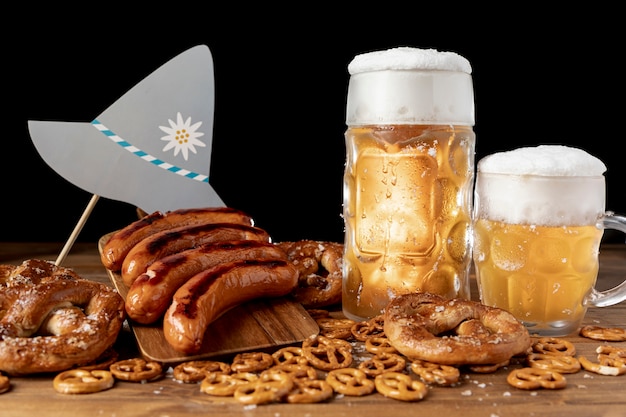 Free photo mugs of beer with sausages on a table