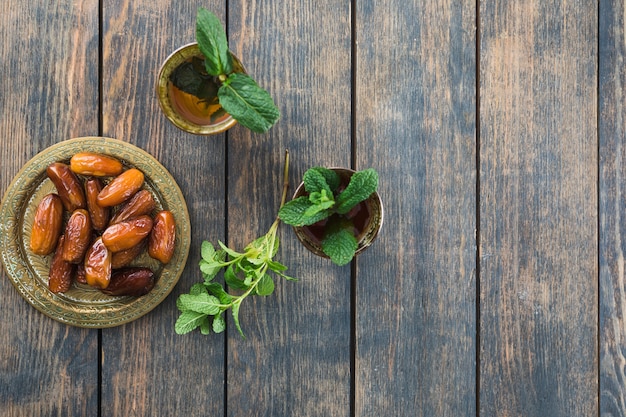 Free photo mugs of drink near dried fruits on saucer