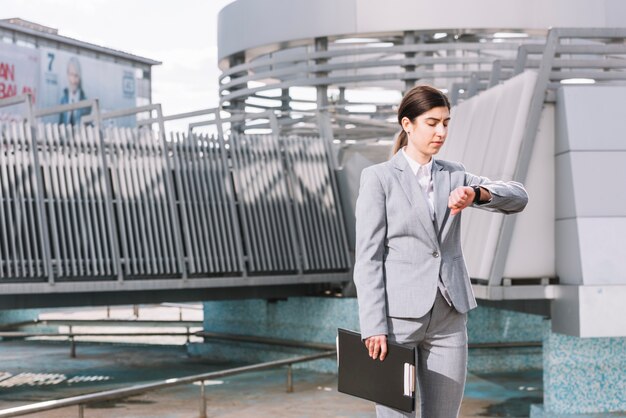 Mujer de negocios moderna mirando el reloj al aire libre