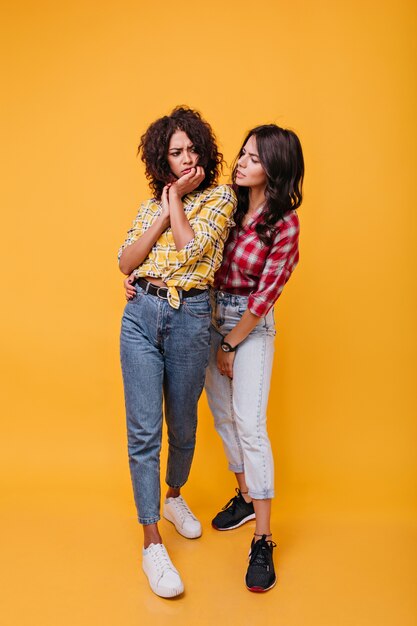 Mulatto in yellow blouse is upset and her best friend comforts her. Girls with curls discuss sad story.