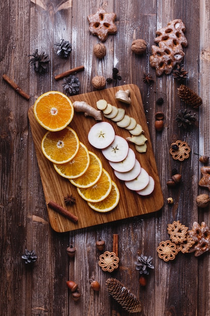 グリューワインの調理オレンジ、リンゴ、種は木製のテーブルの上にあります。