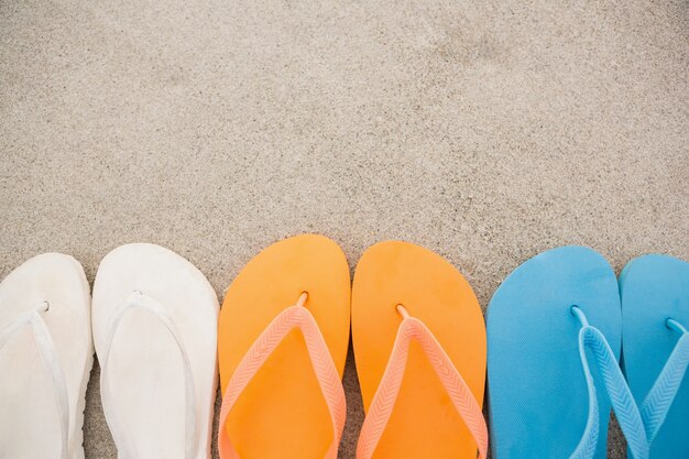 Multi-color flip flops arranged in a row in sand