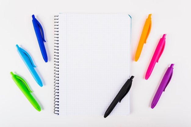 Free photo multi-colored pens with notebook