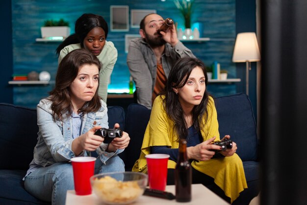 Multi ethinc friends cheerful group of people relaxing on console games with controller