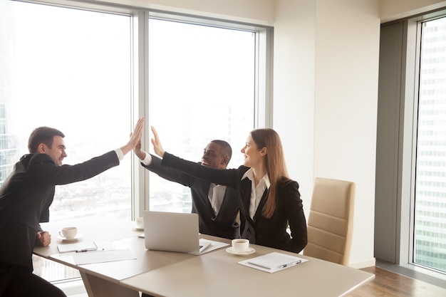 Multi-ethnic business partners giving high five on meeting, cele