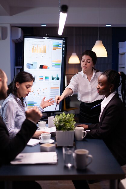 Multi-ethnic businesspeople discussing financial company solution sitting at conference table in meeting room