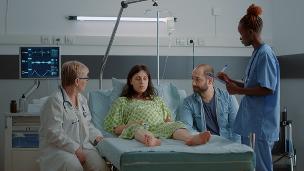 Multi ethnic doctor and nurse talking to pregnant woman