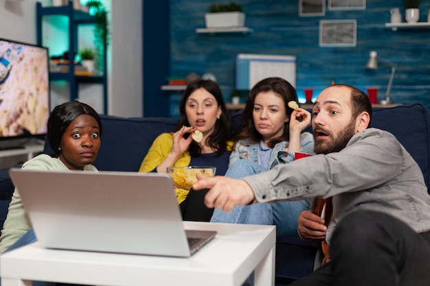 Foto gratuita amici multietnici che trascorrono del tempo insieme guardando l'intrattenimento sul laptop parlando dello stile di vita. gruppo di persone multirazziali che si rilassano e si divertono a rilassarsi durante la serata al cinema, uscire