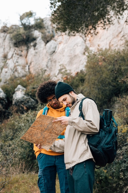 Multi ethnic male hiker finding the destination on map in the forest