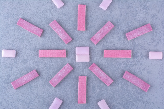 Free photo multi-linear arrangement of bubblegum strips and tablets on marble surface