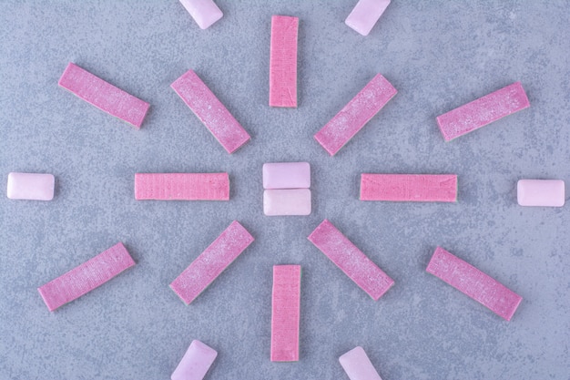 Multi-linear arrangement of bubblegum strips and tablets on marble surface