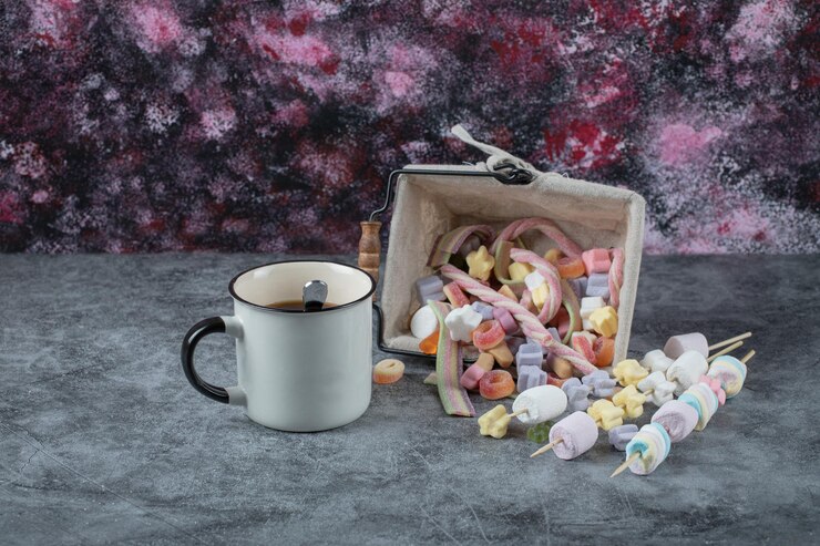 Free Photo multicolor marshmallows on basket with a cup of tea aside.