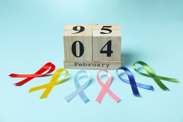 Multicolored awareness ribbons and calendar with 4 february on blue background