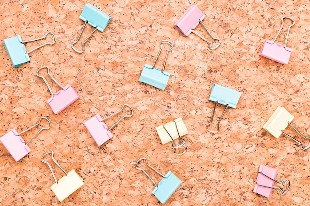 Free photo multicolored binder clips on wooden desk