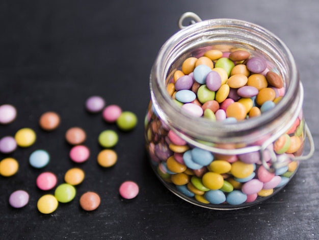 Multicolored glazed candies in glass jar