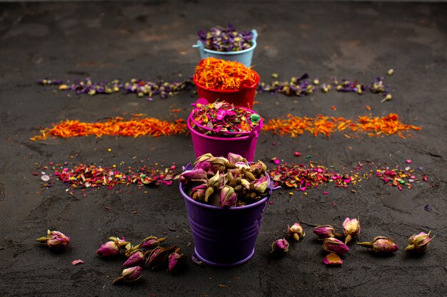 Multicolored leafs flower and other colorful particles in pots on a grey desk