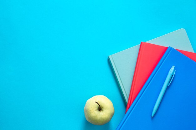 無料写真 色とりどりのメモ帳と青い背景の上面にリンゴ
