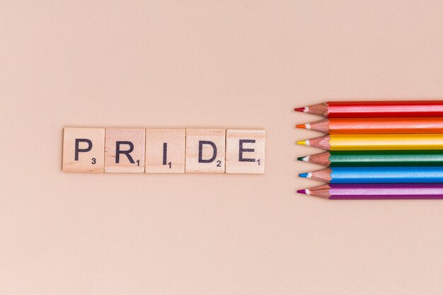 色とりどりの鉛筆とベージュ色の背景上のPRIDEのテキスト