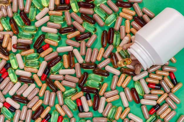 Разноцветные таблетки и капсулы на зеленом фоне