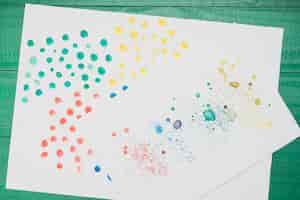 Free photo multicolored stained abstract painting on white paper over green table