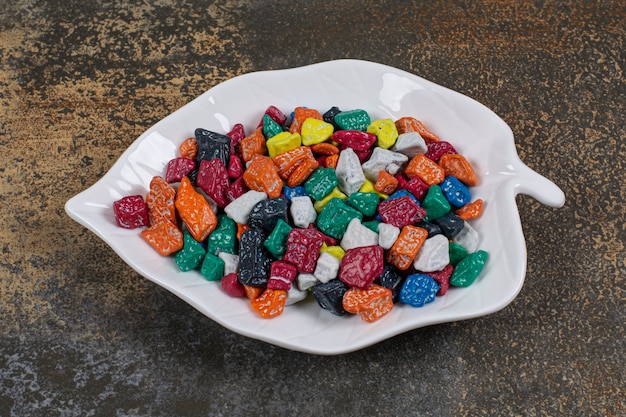 Multicolored stone candies on leaf shaped plate.