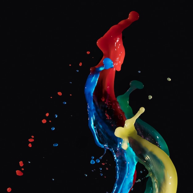 Multicolored watercolor paint splashing together against dark backdrop