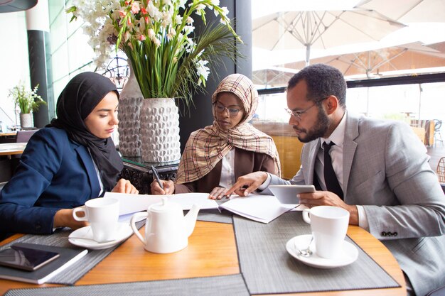 Многокультурные деловые партнеры обсуждают контракт в кафе