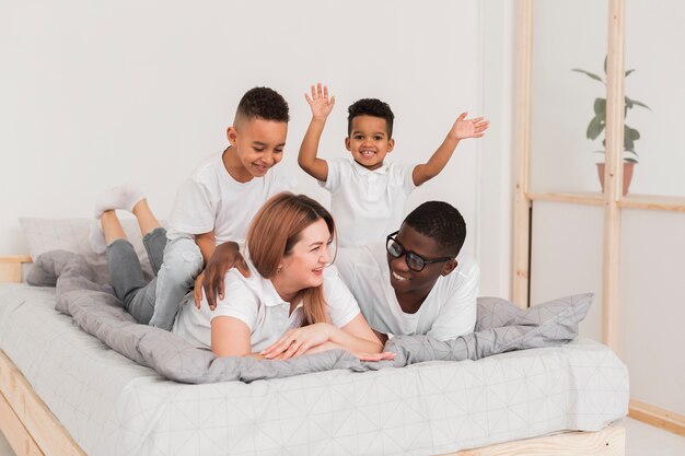 Multicultural family staying in bed together