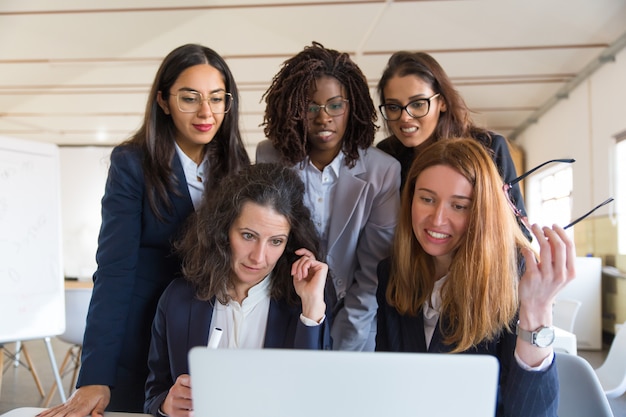 Free photo multiethnic businesswomen using laptop in office