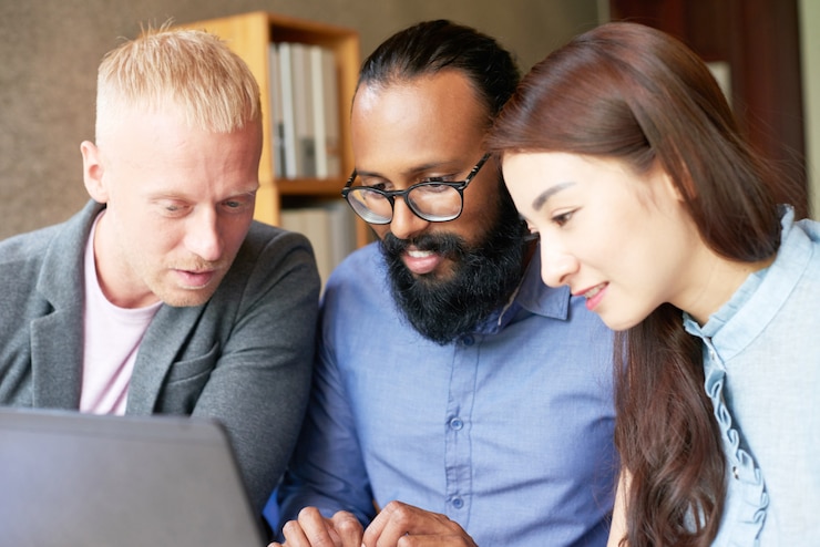 Free Photo multiethnic colleagues working on laptop together in office and looking at screen