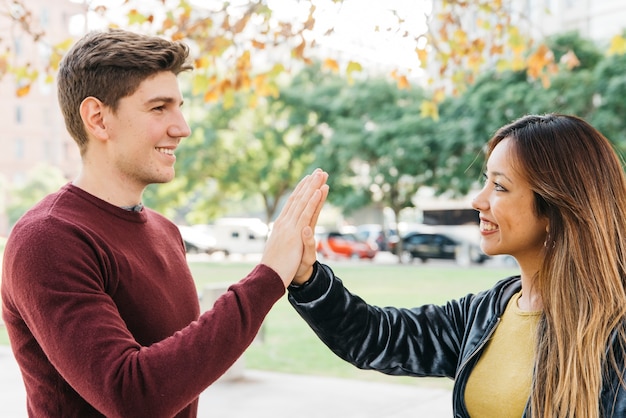 Free photo multiethnic couple giving high five and smiling