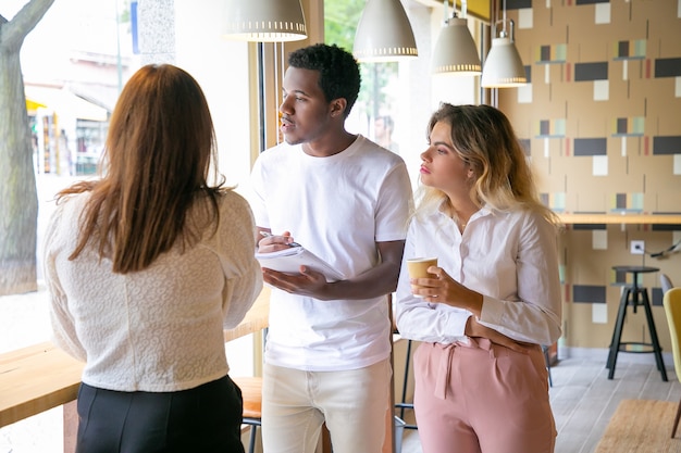 Free photo multiethnic designers standing near window and looking at street