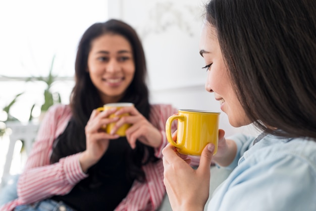 Multiethnic girlfriends talking and drinking tea