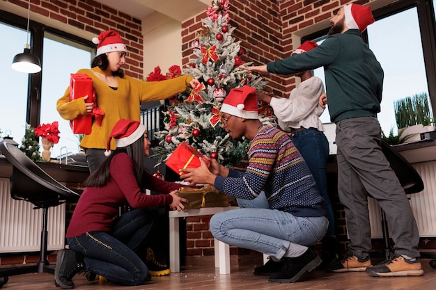다민족 동료들은 축제 장식품과 크리스마스 트리로 사무실을 장식하고 선물과 선물을 줍니다. 직장에서 겨울 동안 크리스마스 휴일 전통을 축하합니다.