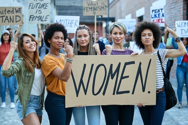 Multiethnic group of females flexing their biceps while participating in a protests for women's rights