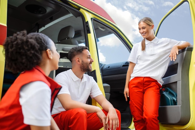Мультиэтнические фельдшеры стоят у машины скорой помощи Врач скорой помощи и медсестра стоят перед машиной скорой помощи