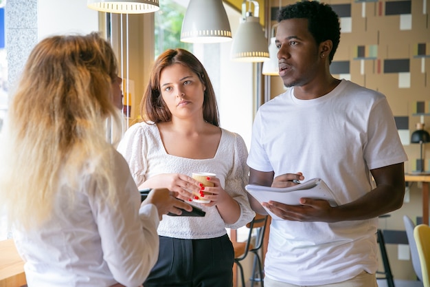 Foto gratuita partner multietnici in piedi e discutendo del progetto