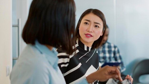 就職の面接で待っているロビーで会話をし、列に並んで人事部とのミーティングを開始するのを待っている間に雇用について話している女性の多民族チーム。採用選考