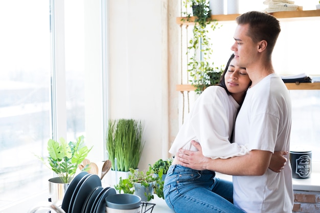 Foto gratuita giovani coppie multietniche nell'amore che abbraccia in cucina