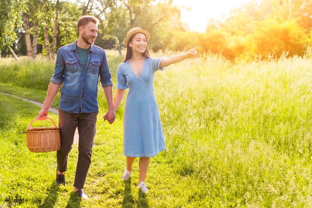 Multiethnic young enamored couple walking in park holding hands