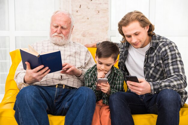 Multigenerational men reading book and smartphones 