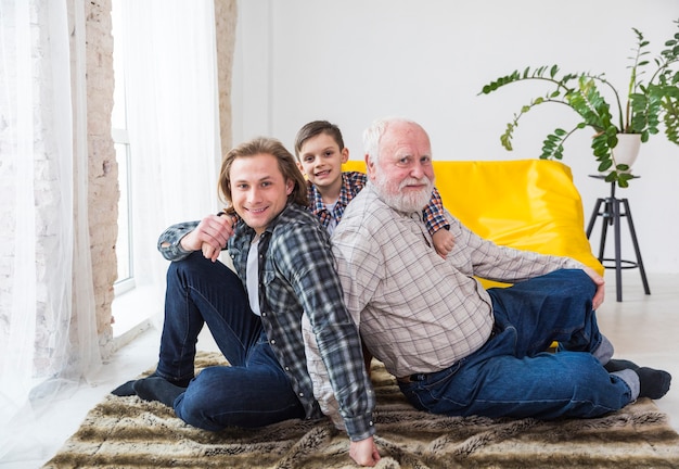 Free photo multigenerational men sitting on carpet at home