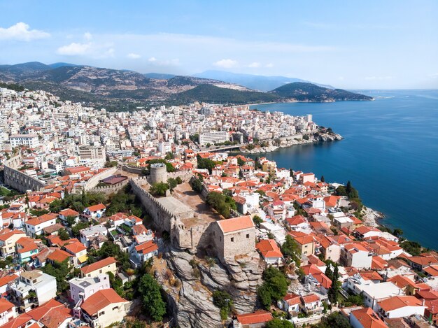 Multiple buildings and fort, green hills on the background in Kavala, Greece